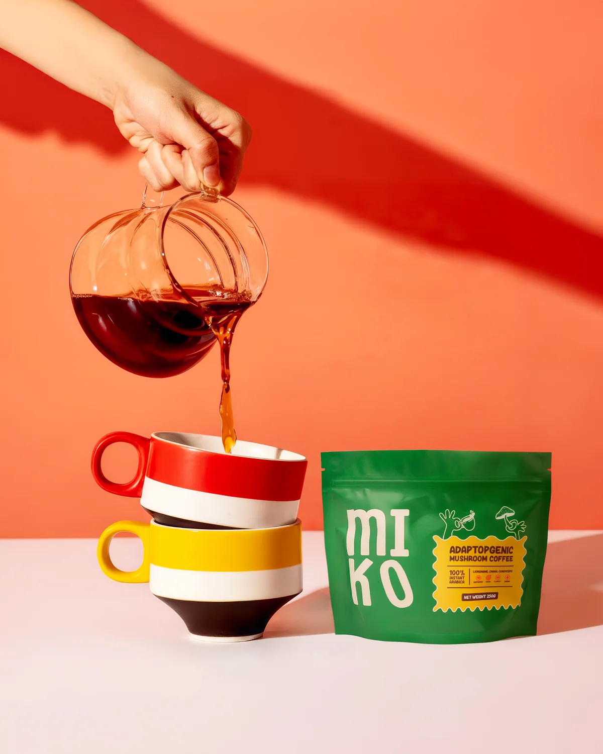MIKO mushroom coffee poured into striped mugs beside the 250g pouch